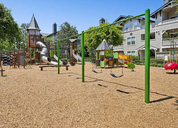 Walkway alongside apartment building with landscaping and fenced playground at The Presidio