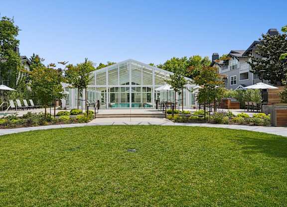 Pool house exterior with landscaped pathways, lawn space, and surrounding greenery at The Presidio Apartments.