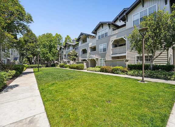A row of houses with a green lawn in front.