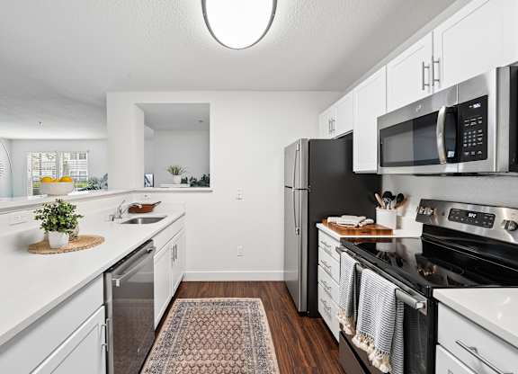 A kitchen with white cabinets and black appliances.
