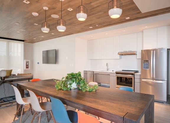 a dining room with a wooden table and chairs and a kitchen with stainless steel appliances