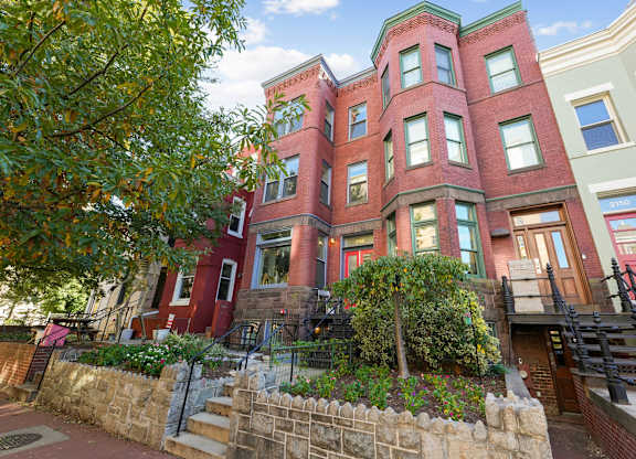 A red brick building with a green tree in front.