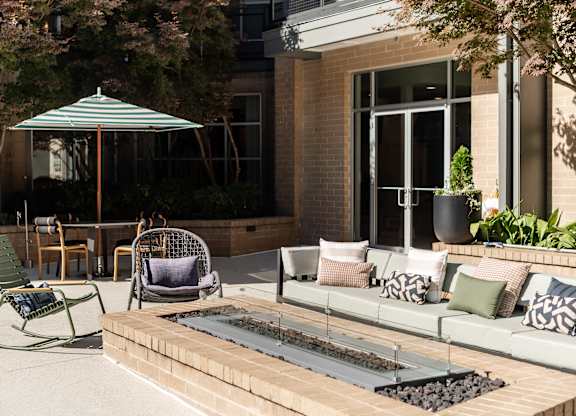 A patio with a couch, chairs, and an umbrella.
