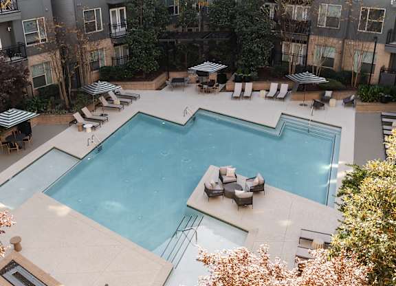 A large outdoor swimming pool surrounded by lounge chairs and umbrellas.