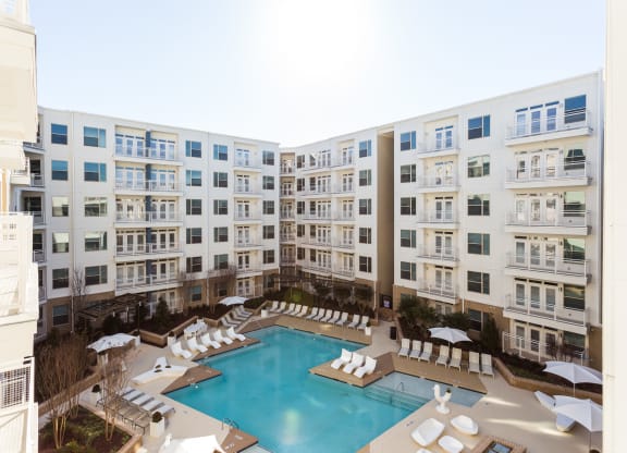 an overhead view of a large pool with white lounge chairs and umbrellas in front of
