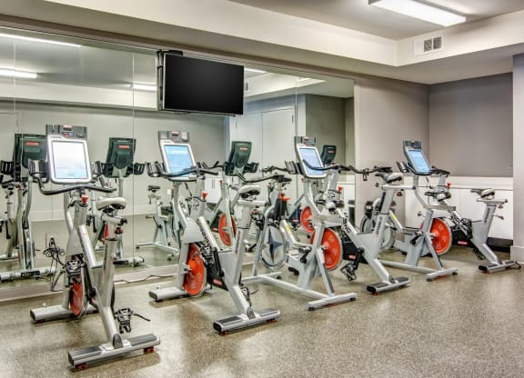 a room filled with lots of cardio equipment and a flat screen tv