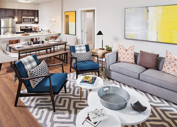 a living room with a couch and chairs and a kitchen