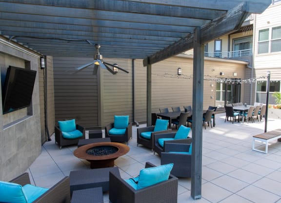 a covered patio with blue chairs and a fire pit