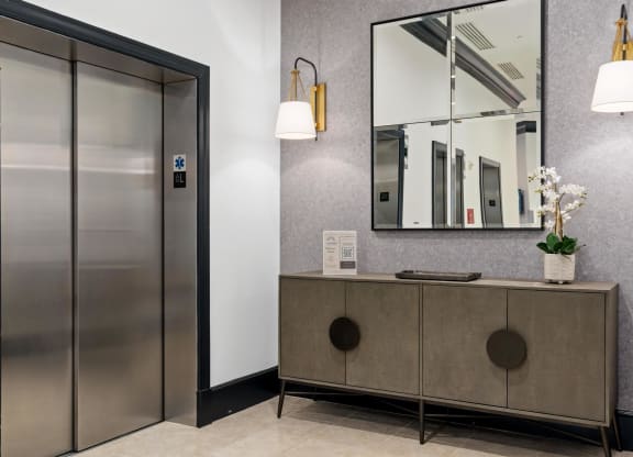 a lobby with a cabinet and a mirror and a elevator