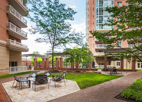 A patio with chairs and a table is surrounded by apartment buildings.