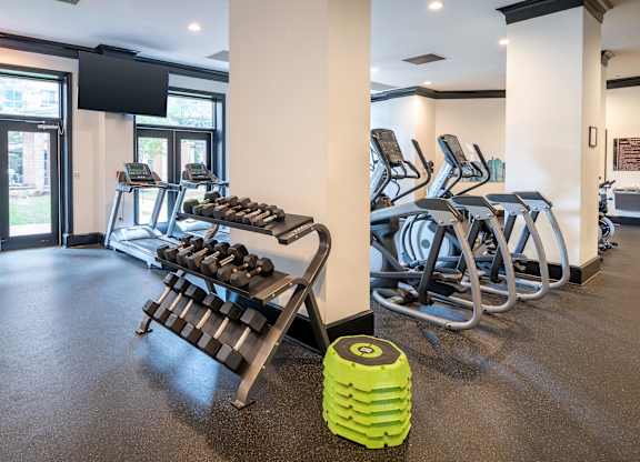 A gym with a green dumbbell holder in the foreground.