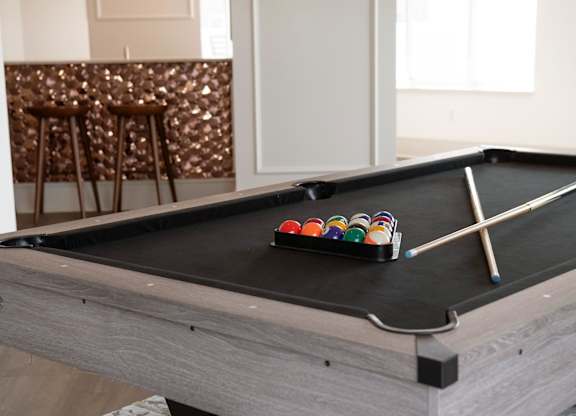 A pool table with a set of cues and balls on it.