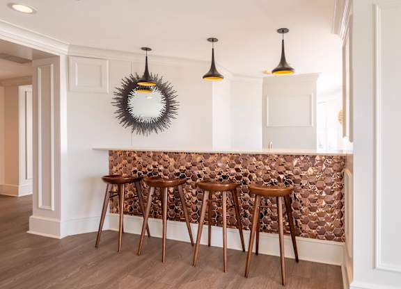 A bar with three stools and a mirror on the wall.