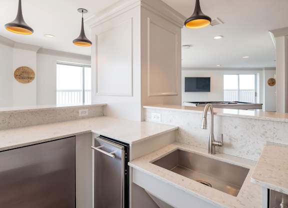 A modern kitchen with a stainless steel dishwasher and a sink with a marble countertop.