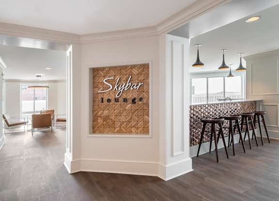 A room with a wooden floor and a wall hanging with the word Skybar on it.