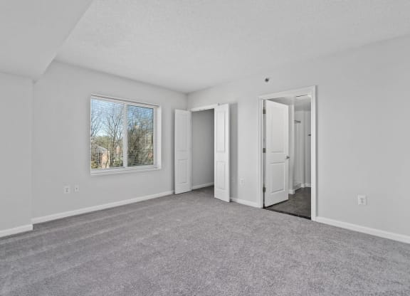 an empty living room with white walls and a window