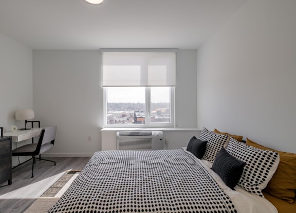 a bedroom with a bed and a desk and a window