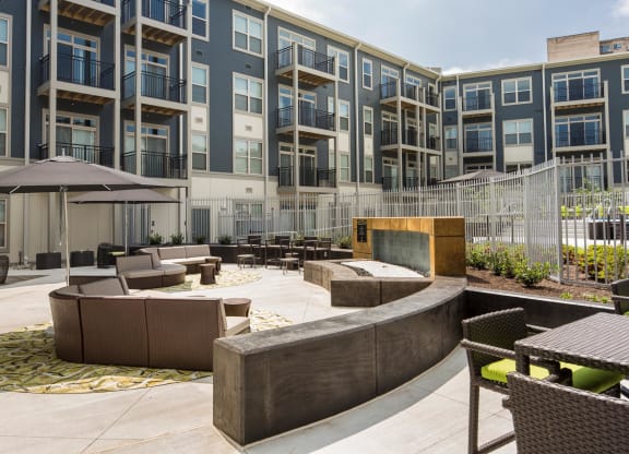 a courtyard with furniture and a fire pit in front of an apartment building