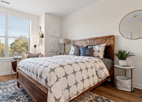 A bedroom with a large bed and a window with blinds.