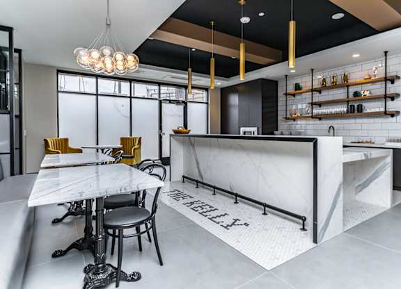 A modern kitchen with a marble island and bar stools.