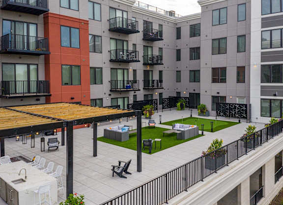 A patio area with a table and chairs is surrounded by apartment buildings.