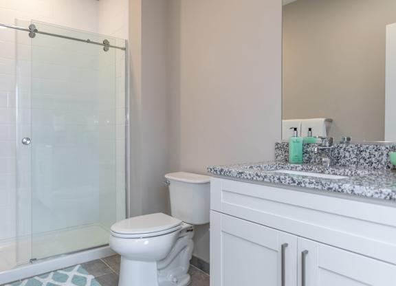 A white toilet sits next to a glass shower door in a bathroom.