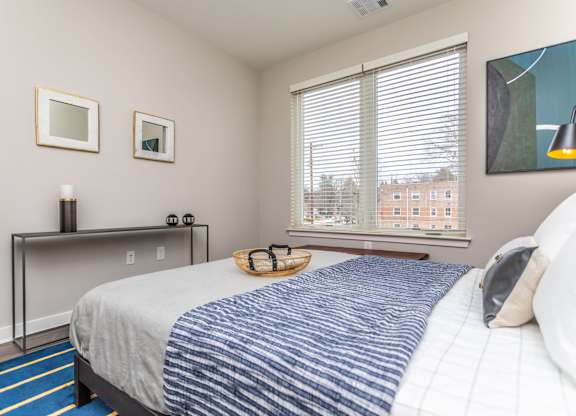 A bedroom with a bed, a table with candles, and a window with blinds.
