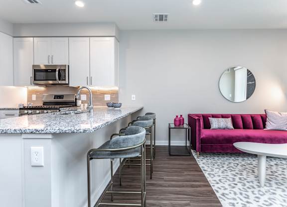 A modern kitchen with a pink couch and a marble countertop.