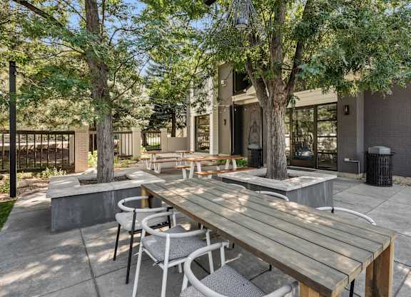 A wooden table is surrounded by chairs in a courtyard at The Magwood in Boulder, Colorado.