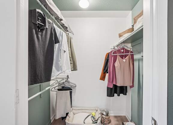 A small closet with clothes hanging on a rail and a white shelf at The Magwood in Boulder, Colorado.
