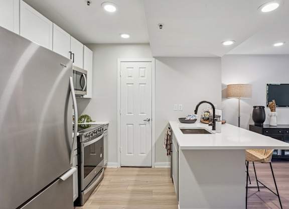 A modern kitchen with a stainless steel refrigerator and white cabinets at The Magwood in Boulder