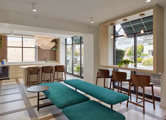 A modern living room with a green sofa and wooden chairs.