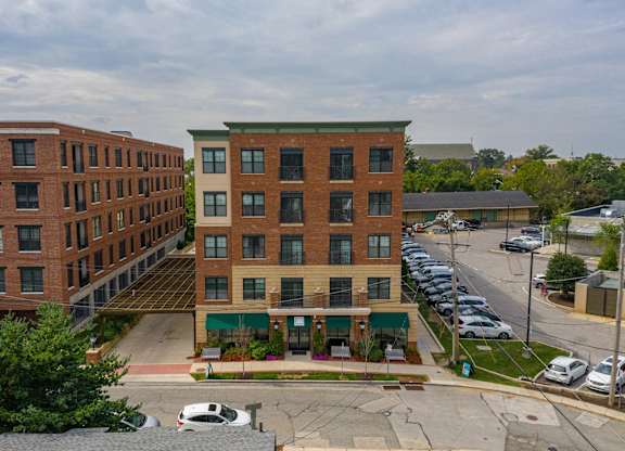 A parking lot is in front of a building with a green awning.