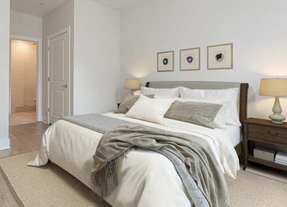 A bedroom with a bed, nightstand, and lamp.