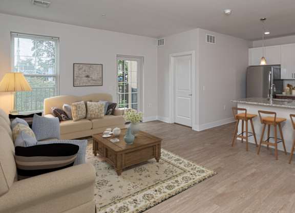 A well-lit, modern kitchen with a breakfast bar and a living room area with a sofa and coffee table.