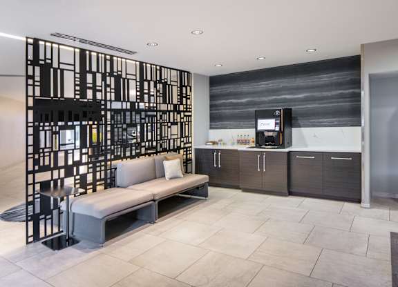 Vantage Mosaic hospitality bar with a beverage machine, dark cabinetry, counter space, bench seating and black screen divider.