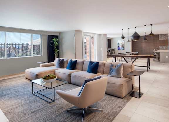 Wide view of The Lounge at Vantage Mosaic with sectional seating, dining tables, an entertaining kitchen and shuffleboard.