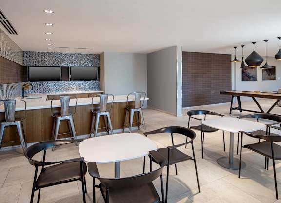Entertaining kitchen in The Lounge with an island, bar seating, round dining tables and a shuffleboard table.