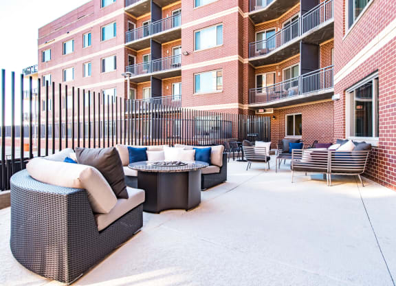 a patio with furniture and a fire pit in front of an apartment building