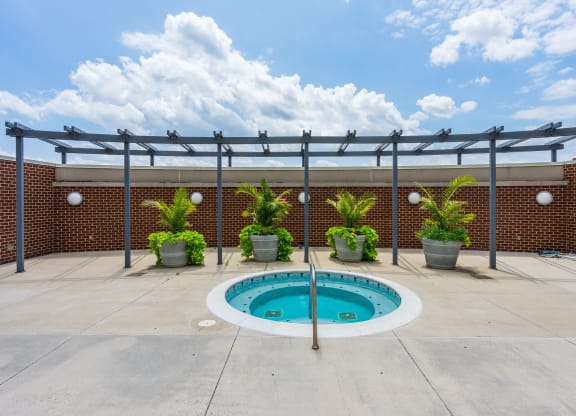 a pool with a brick wall and a patio with potted plants