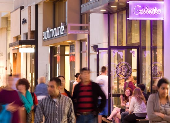 people walking down a city street at night in front of shops