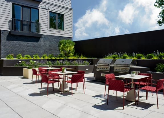 an outdoor patio with tables and chairs and barbecue grills