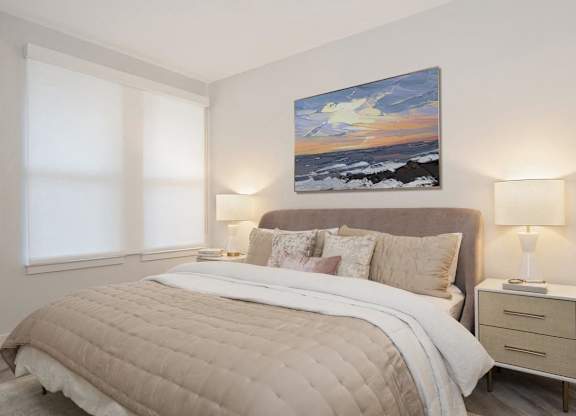 A bedroom with a large bed, a nightstand with a lamp, and a painting on the wall.