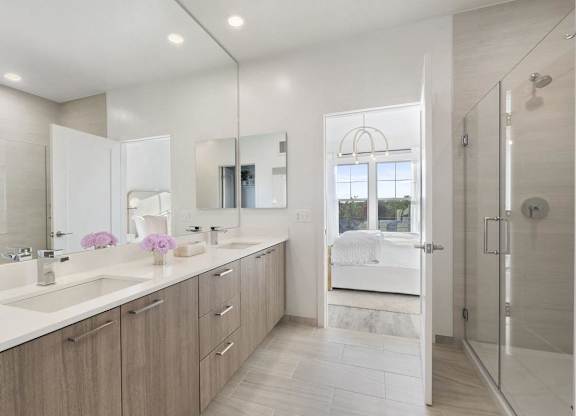 A bathroom with a white counter top and a walk in shower.