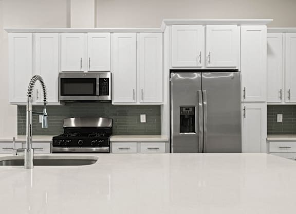 A kitchen with white cabinets and a stainless steel refrigerator.