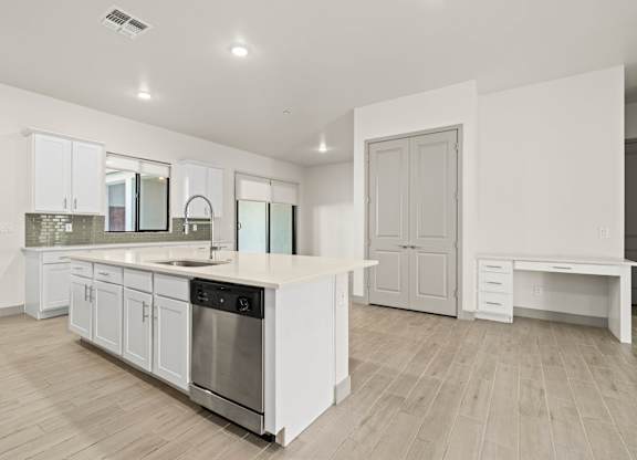 A modern kitchen with white cabinets and a wooden floor.
