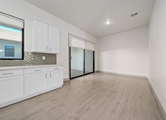 A kitchen with white cabinets and a wooden floor.