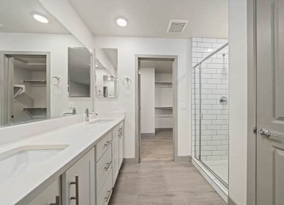 A bathroom with a walk-in shower and double sinks.