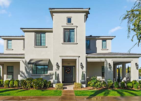 A large, two-story house with a front yard and a driveway.