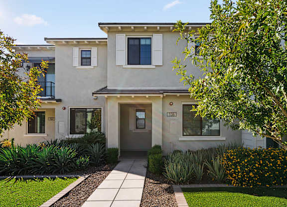 A modern house with a grey front door and a small garden in front.